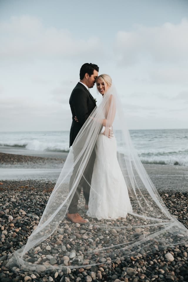 A newlywed couple sharing a wedding portrait on the beach