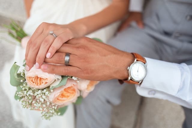 A couple holding hands beside a wedding bouquet